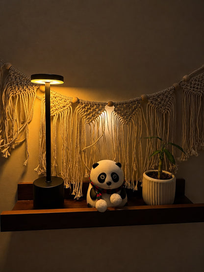 Black Egret Lamp on a shelf with a macramé wall hanging, panda plush toy and potted plant