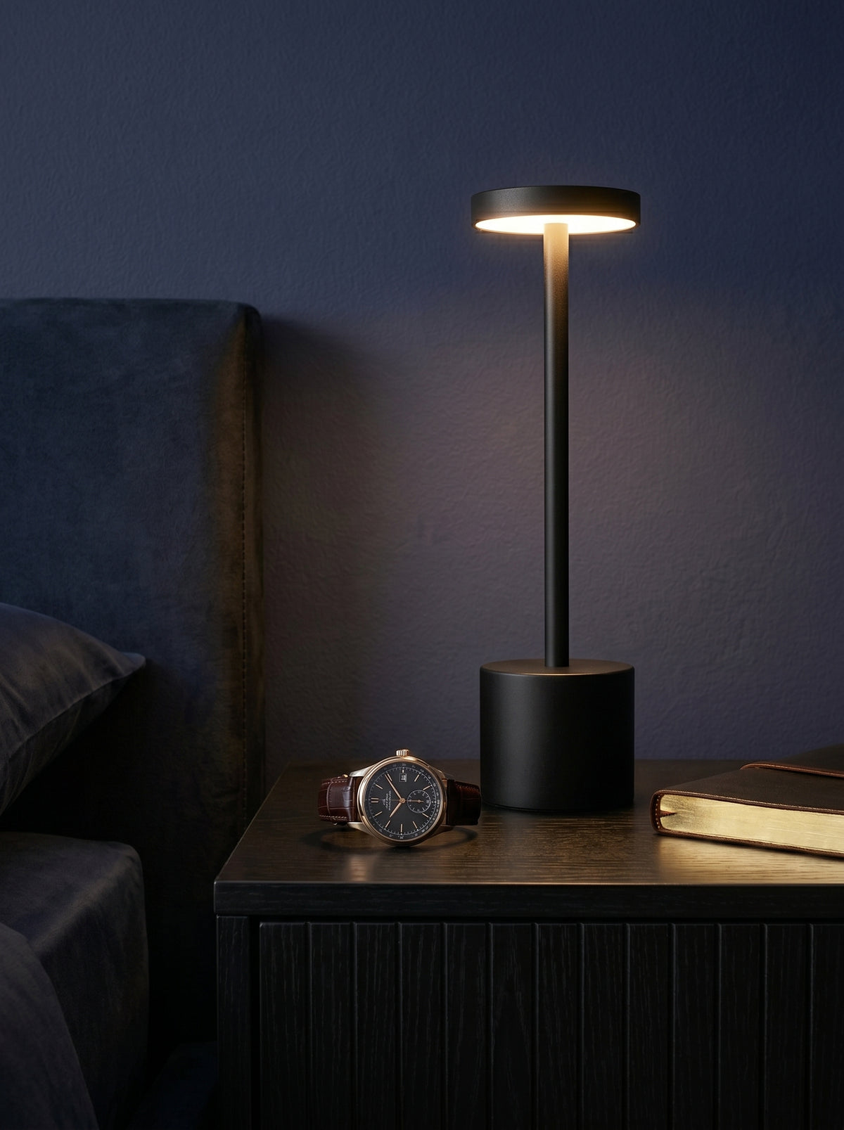 Black Egret Lamp on a bedside table beside a wristwatch in a dark bedroom