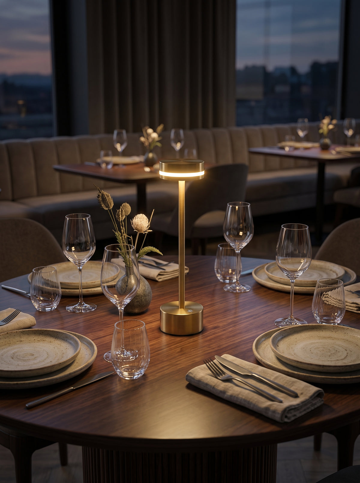 Gold Alba Lamp lighting a restaurant dining table set with wine glasses at dusk
