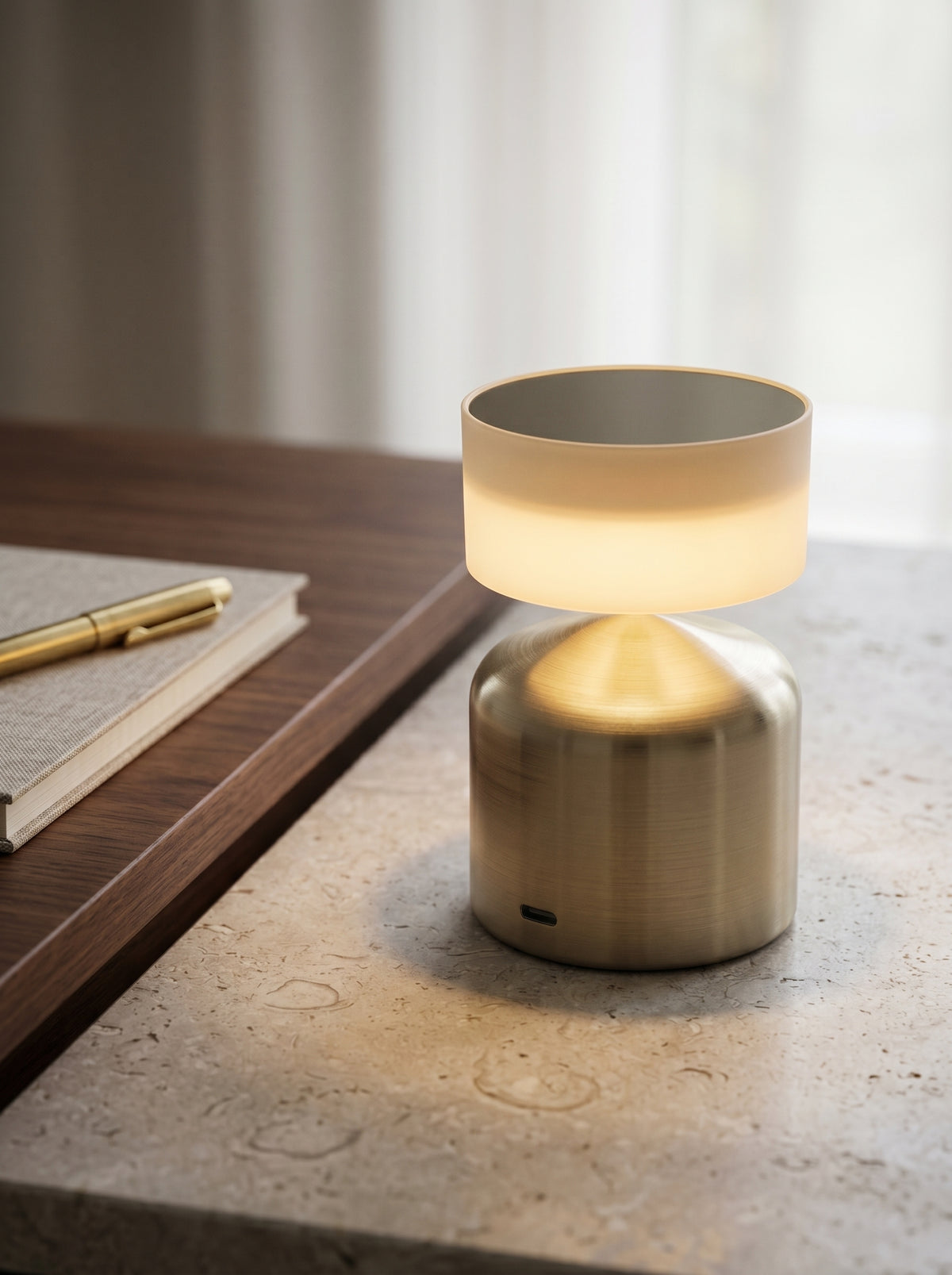 Gold Finch Lamp glowing on a desk beside a notebook and gold pen
