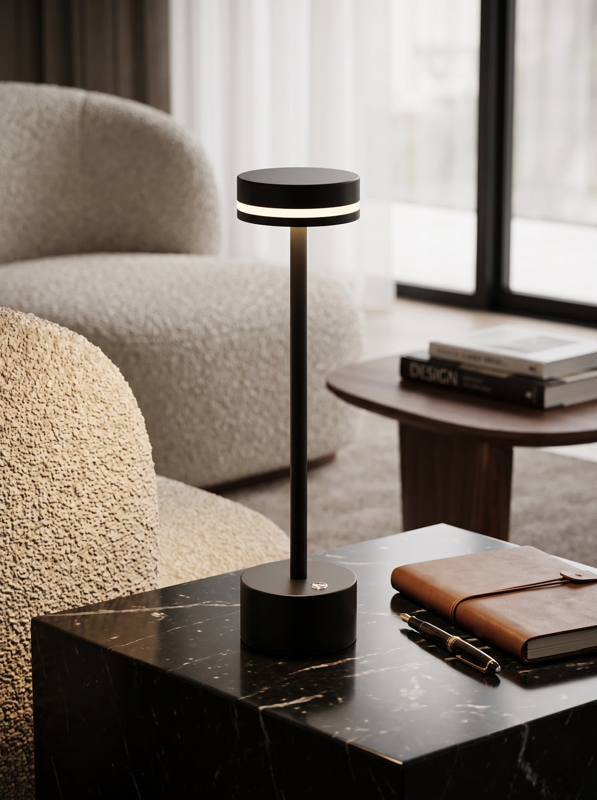 Black Alba Lamp on a black marble side table next to a boucle armchair and leather notebook