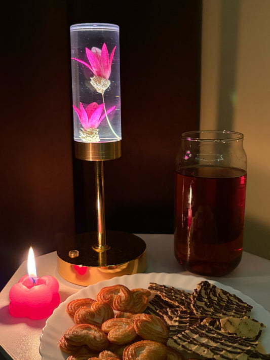 Gold and Pink Phoenix Lamp glowing on a table with a heart-shaped candle, a drink and pastries