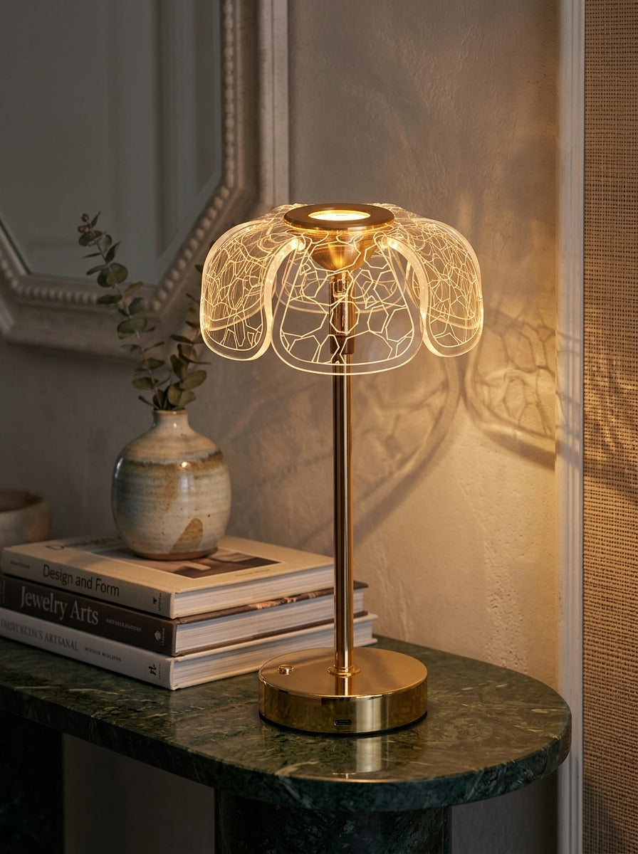 Gold Bubo Lamp, a gold lamp with a clear petal-shaped patterned shade, on a green marble console