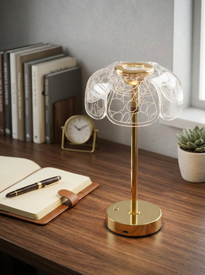 Gold Bubo Lamp on a wooden desk with an open notebook, books and a small clock