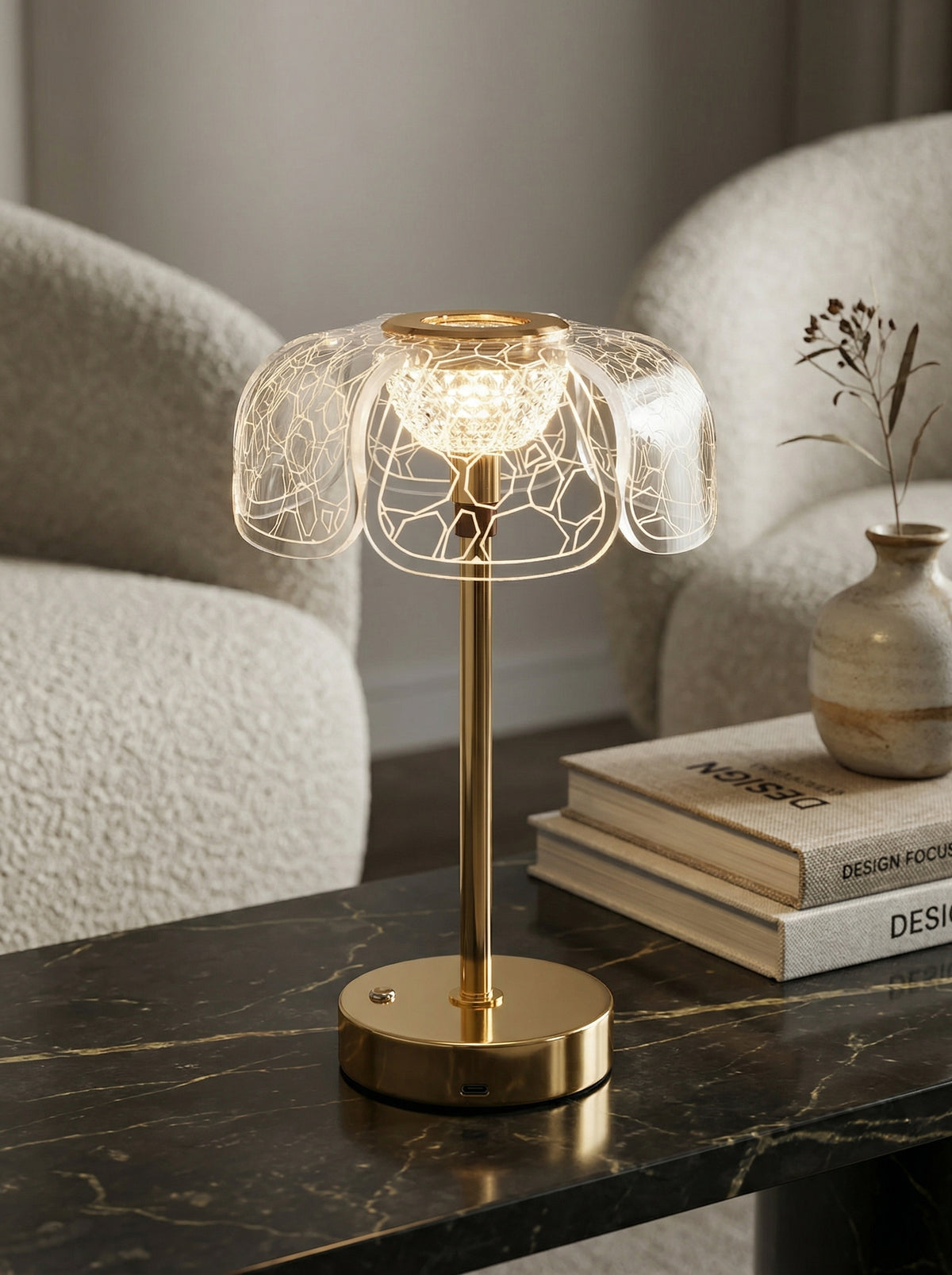 Gold Bubo Lamp on a black marble side table next to a boucle chair and books