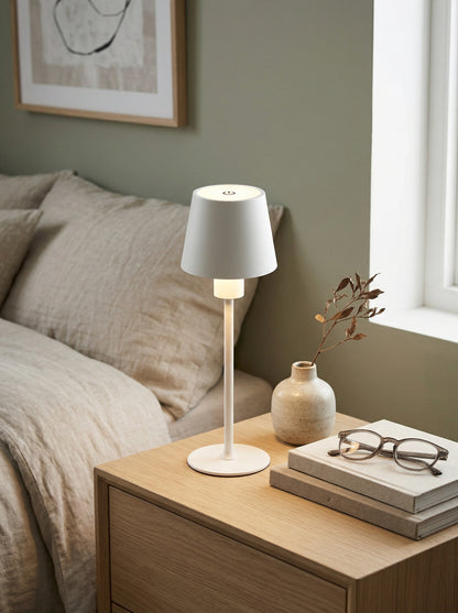 White Ibis Lamp on a wooden nightstand with reading glasses, books and a vase of dried flowers