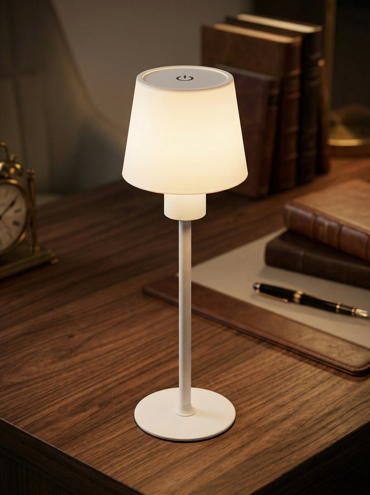 White Ibis Lamp glowing on a wooden desk in front of antique books and a fountain pen