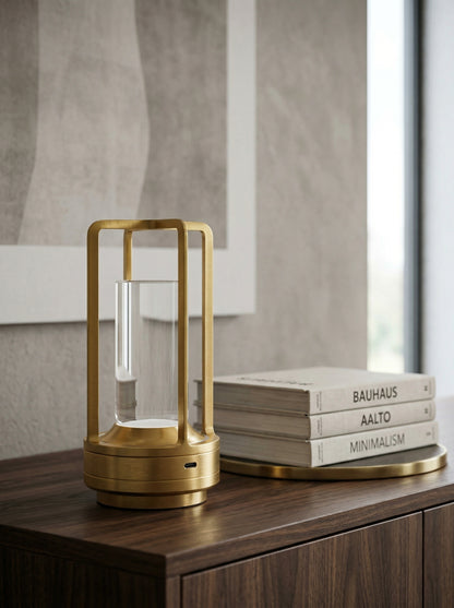Gold Orion Lamp on a wooden sideboard next to a stack of design books