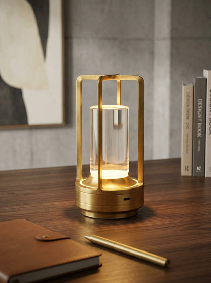Gold Orion Lamp glowing on a wooden desk with a leather notebook and gold pen