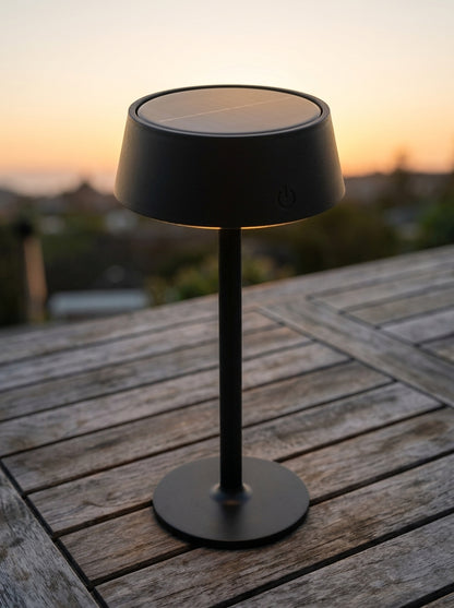 Black Raven Lamp on an outdoor wooden table at sunset