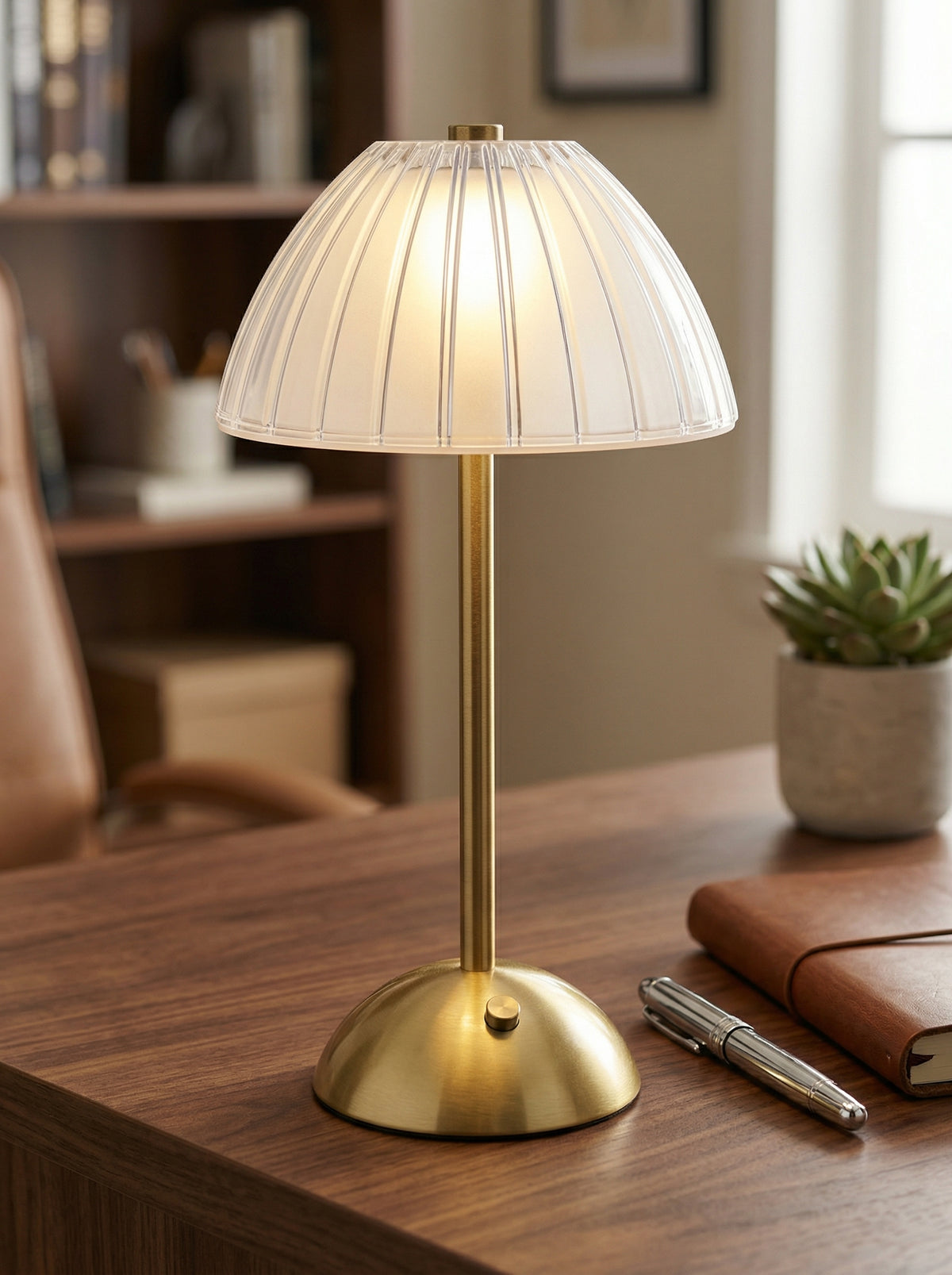 Gold Serin Lamp on a desk with a leather notebook, pen and small succulent