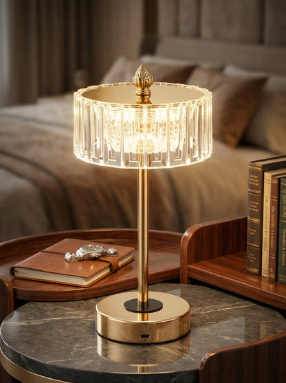 Gold Starling Lamp glowing on a marble bedside table beside books and a leather notebook