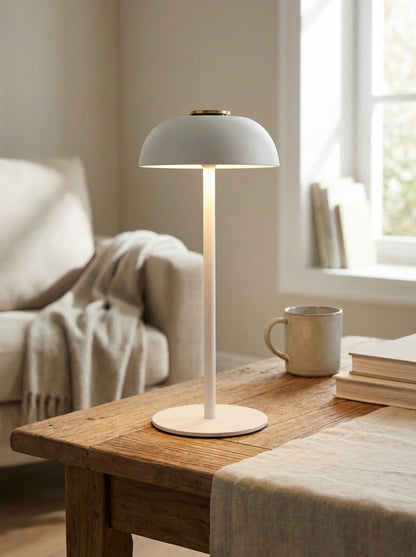 White Swan Lamp with a matte dome shade and slim stem on a wooden table beside a sofa and mug